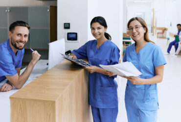 Nurse on duty talking with medical assistants during working day in medical clinic standing near reception desk at hospital lobby. Medical staff of clinic